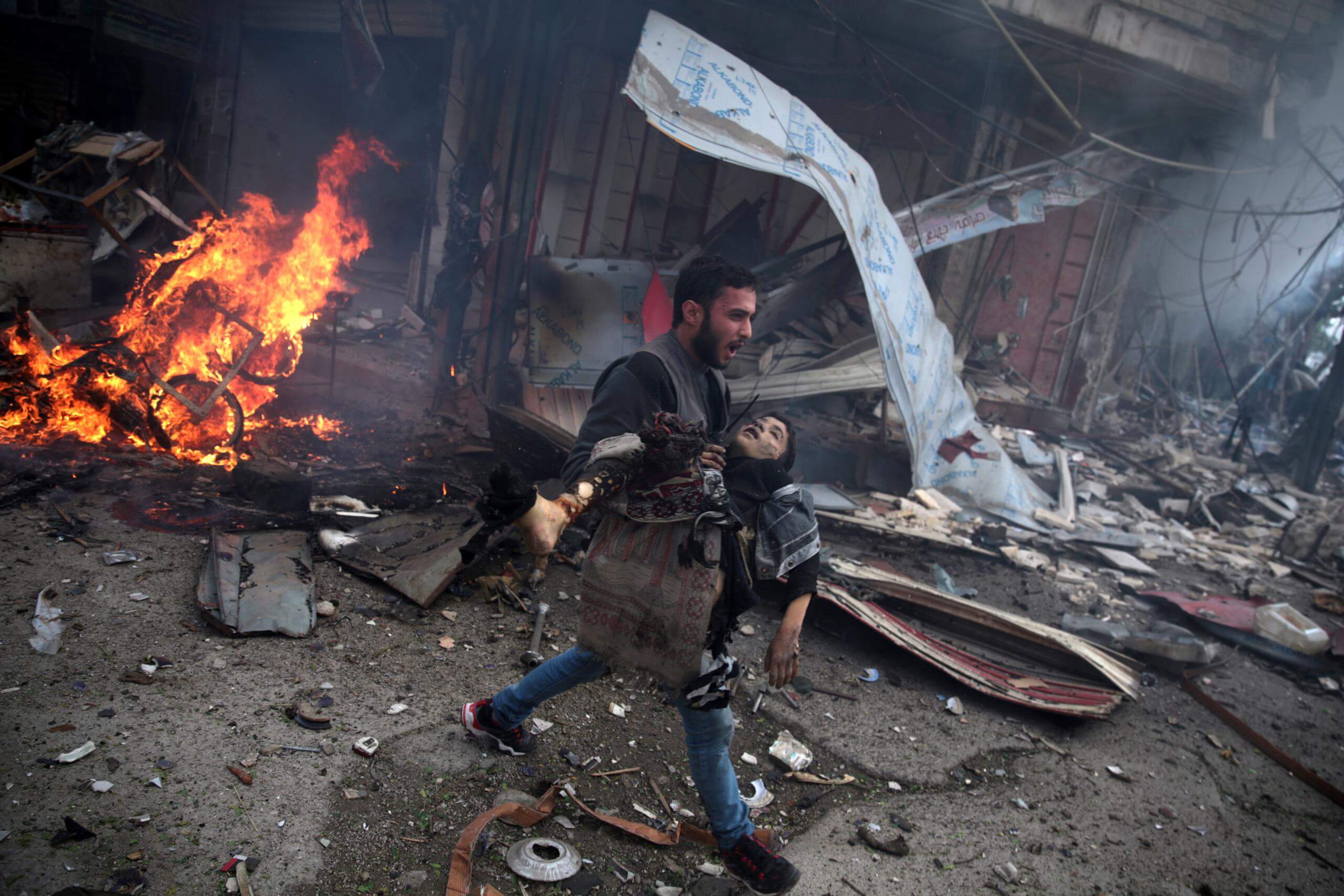 Douma’s Children - por Abd Doumany Homem carregando o corpo de uma criança morte em ataque aéreo (Síria)